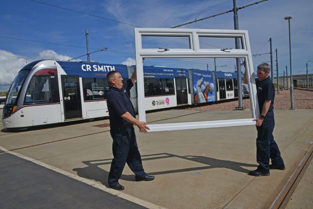 Edinburgh tram sponsored by CR Smith with white Lorimer window frame being held up in front