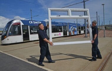 Edinburgh tram sponsored by CR Smith with white Lorimer window frame being held up in front