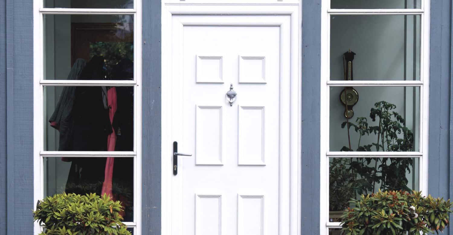 External view of white uPVC front door with urn knocker and lever handle