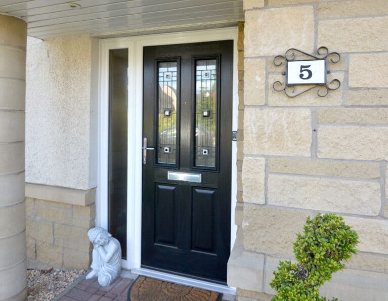 External view of black engineered timber door with two decorative glazed panels and side screen.