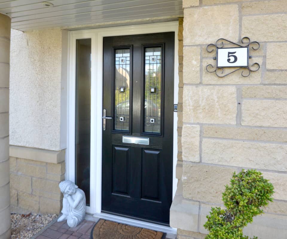 External view of black engineered timber door with two decorative glazed panels and side screen.