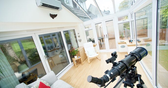 Internal view of white conservatory with climate control system and french doors to the garden