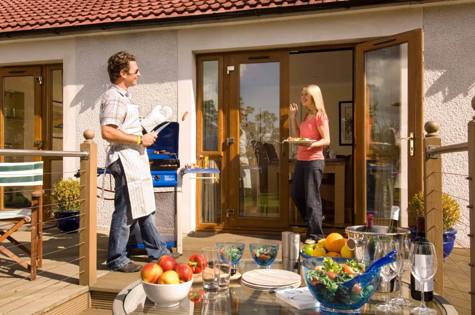 Two people cooking on the barbeque with American light oak french doors