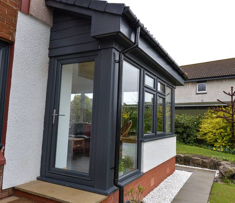 External view of anthracite grey Lorimer sunroom with single door and steps leading to the garden