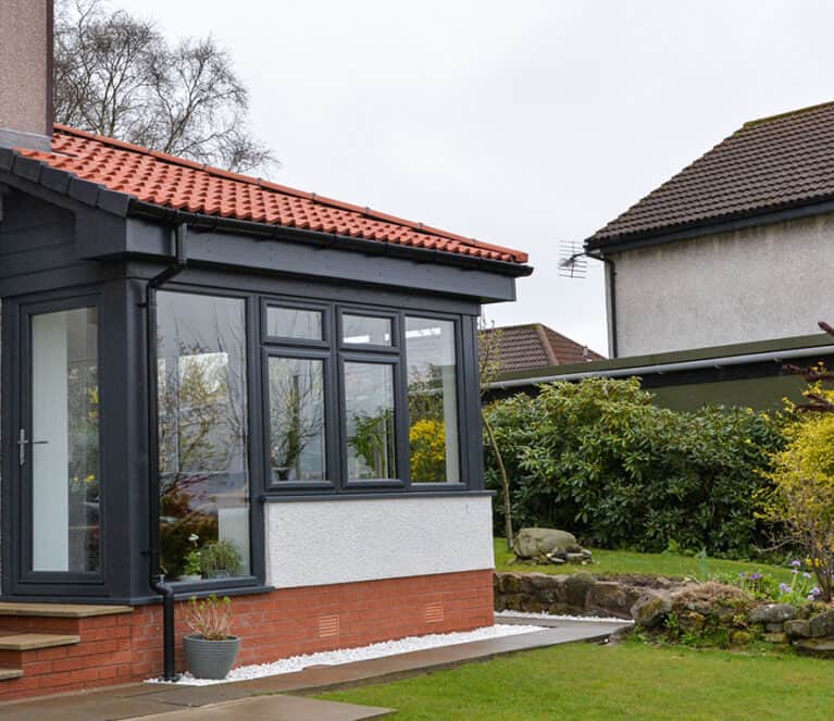 External view of anthracite grey Lorimer sunroom with single door and steps leading to the garden