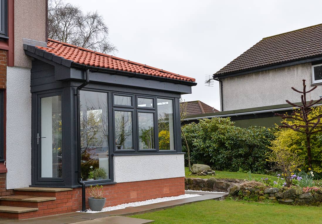 External view of anthracite grey Lorimer sunroom with single door and steps leading to the garden