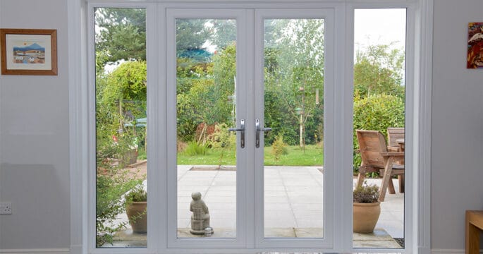 Kitchen diner with white french doors with side screens leading out onto the patio