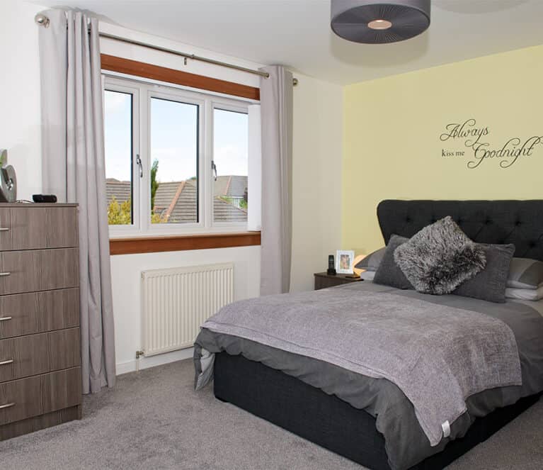 Bedroom with large casement window with timber surrounds and grey curtains