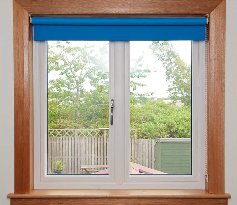 White casement window with timber sill and surrounds and blue roller blind