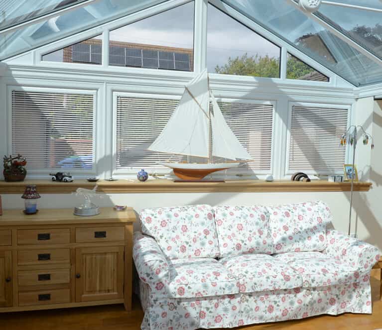 Internal view of gable front conservatory with floral sofa and side cabinet