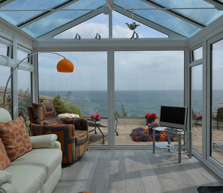 Gable front white conservatory with blue tinted smartglass roof and french doors