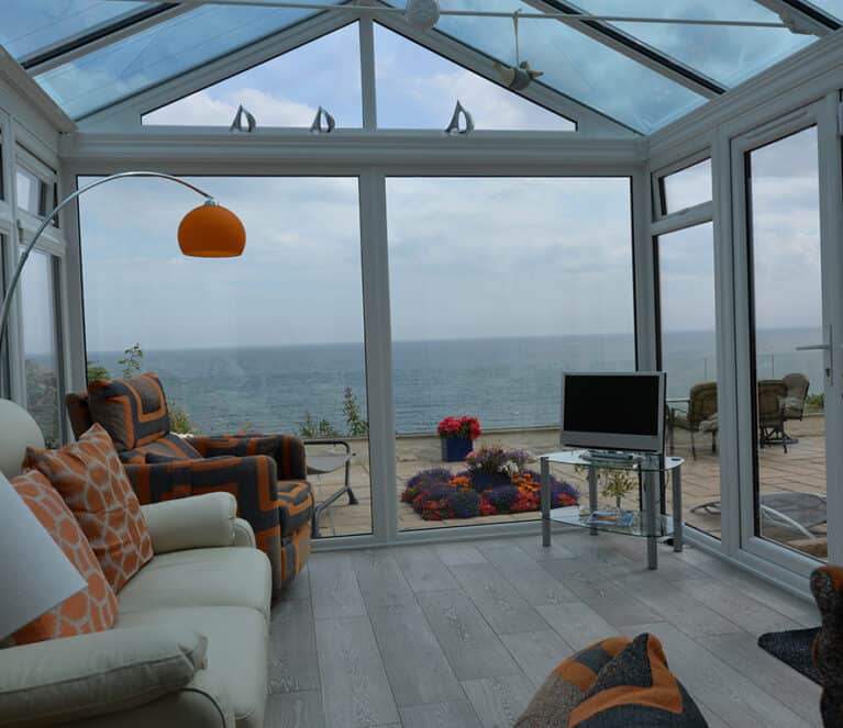 Gable front white conservatory with blue tinted smartglass roof and french doors