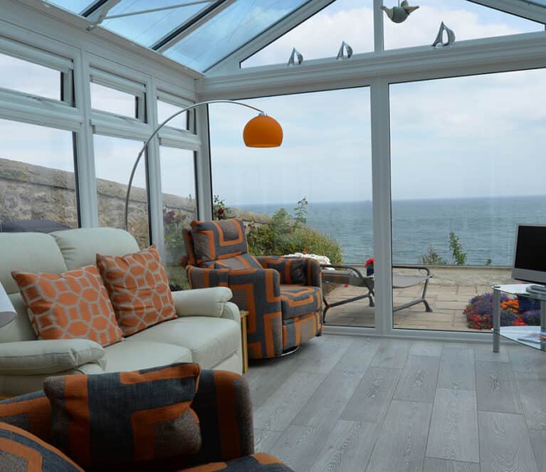 Gable front white conservatory with blue tinted smartglass roof and french doors