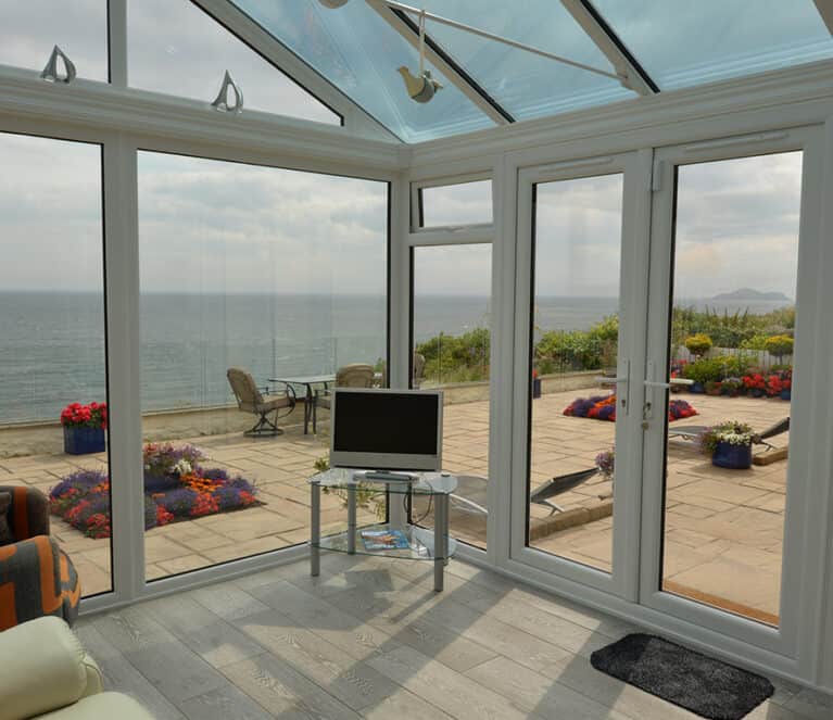 Gable front white conservatory with blue tinted smartglass roof and french doors