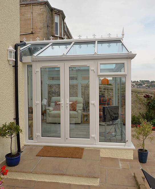 Gable front white conservatory with blue tinted smartglass roof and french doors