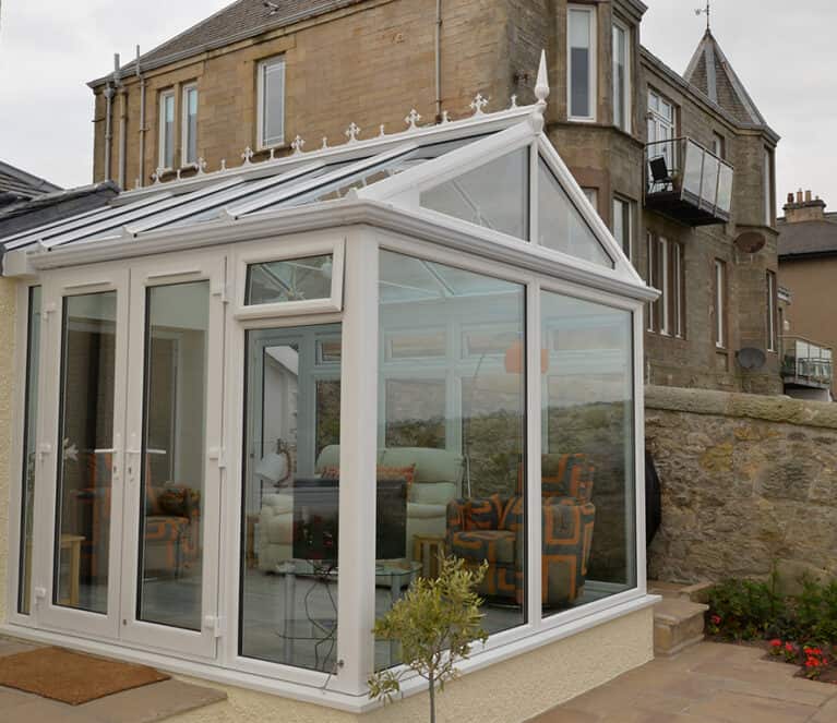 Gable front white conservatory with blue tinted smartglass roof and french doors