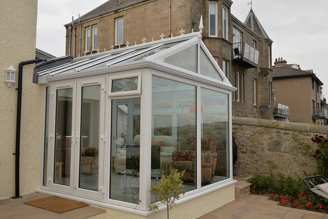 Gable front white conservatory with blue tinted smartglass roof and french doors
