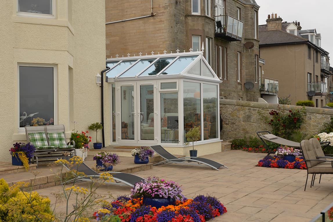 Gable front white conservatory with blue tinted smartglass roof and french doors