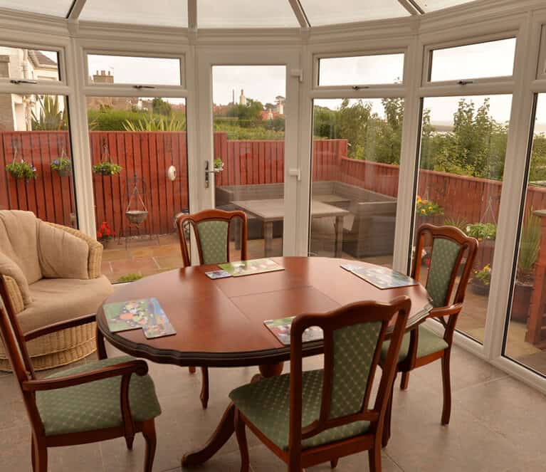 White victorian shaped conservatory with floor to ceiling glazing and grey tinted smartglass roof