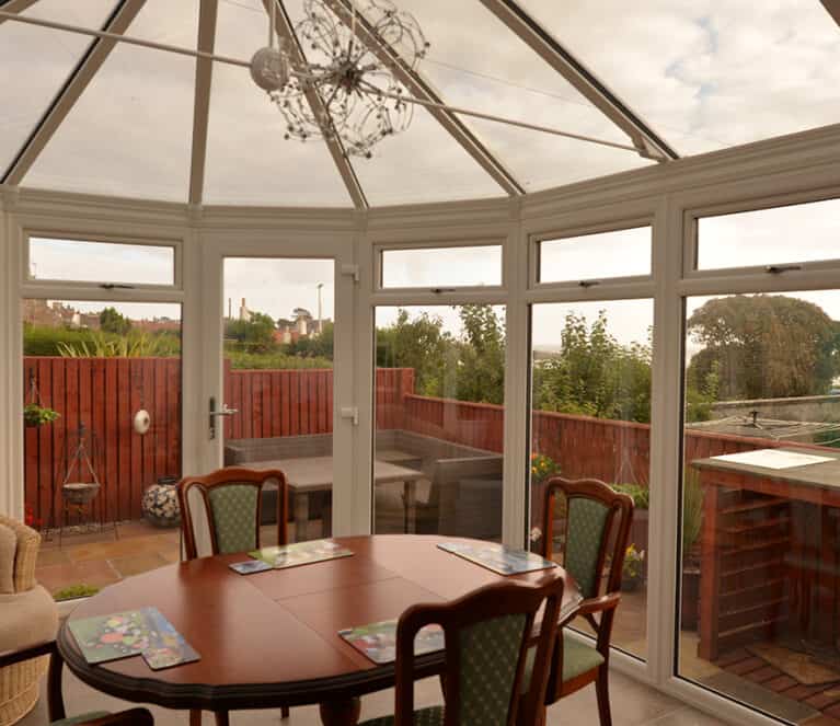 White victorian shaped conservatory with floor to ceiling glazing and grey tinted smartglass roof