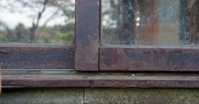 Before photo. Close up of a rotting timber framed sliding patio door