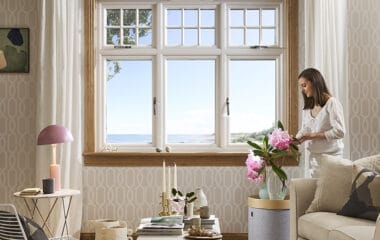 Living room with lorimer casement window and woman arranging flowers. The double-glazed window is complete with oak sills and surrounds.