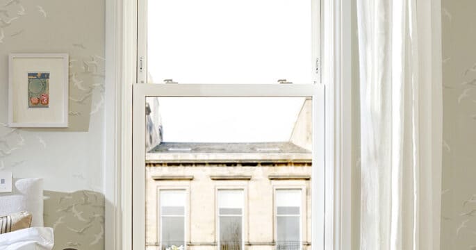 White sliding sash window with white sills and surrounds in a bedroom