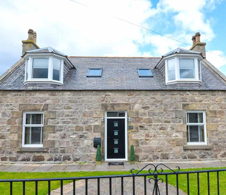External view of home in Buckie with white windows and black front door