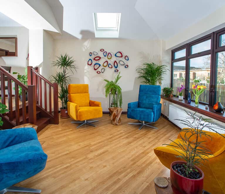 Internal view of sunroom with rosewood windows and brightly coloured chairs