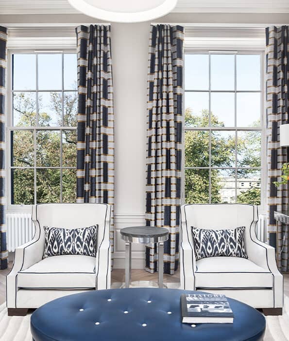 Blue and white living room with large windows and pattered curtains