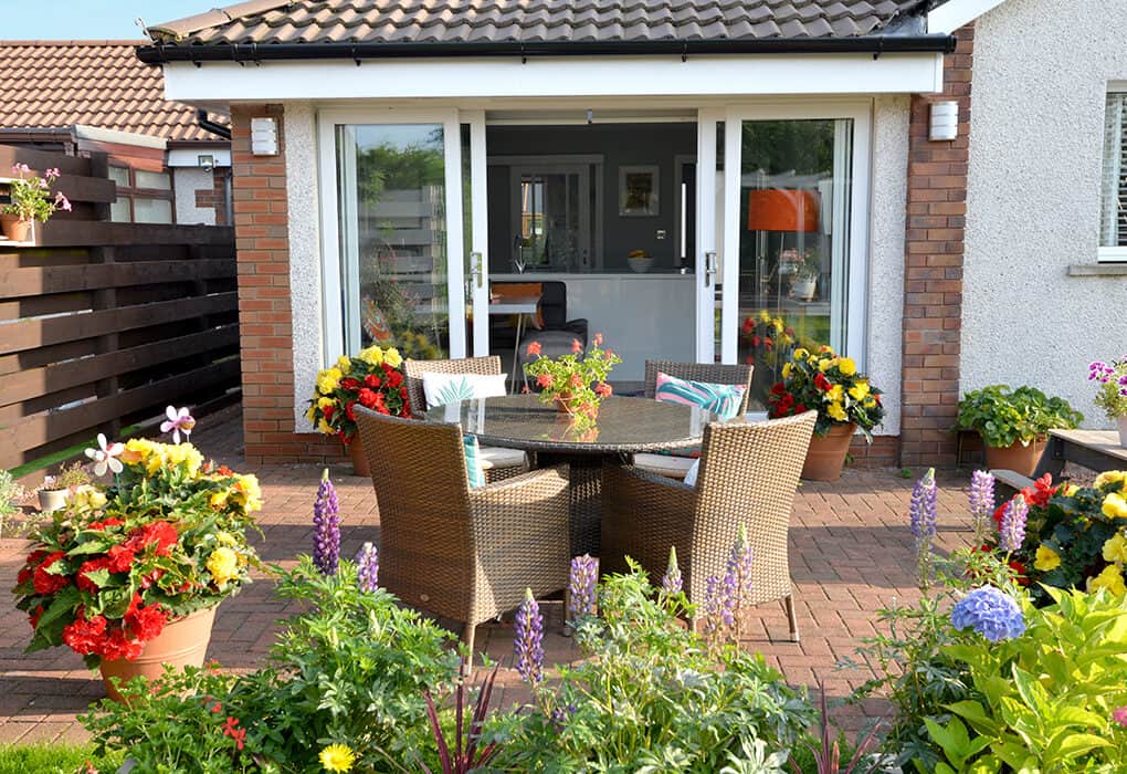 External view from the garden of open, white patio doors