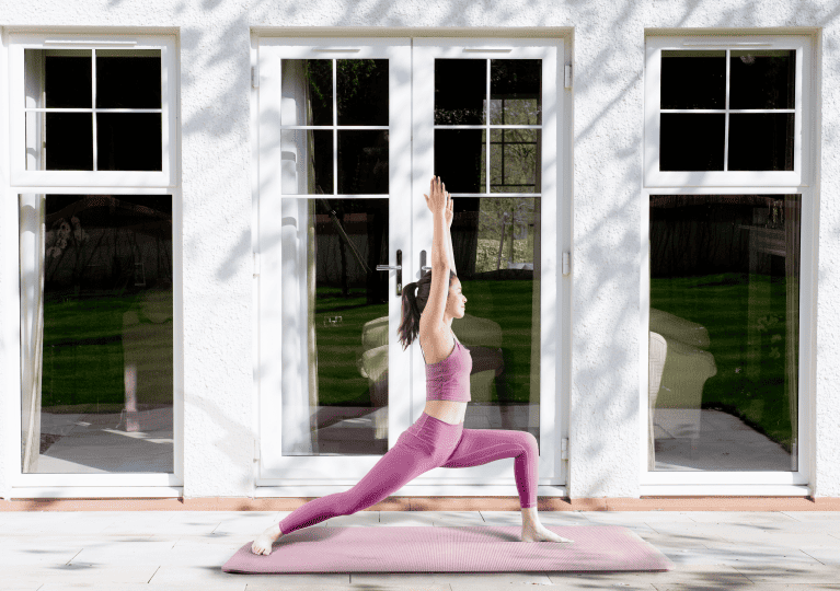 Woman practicing yoga in front of Lorimer french doors and casement windows