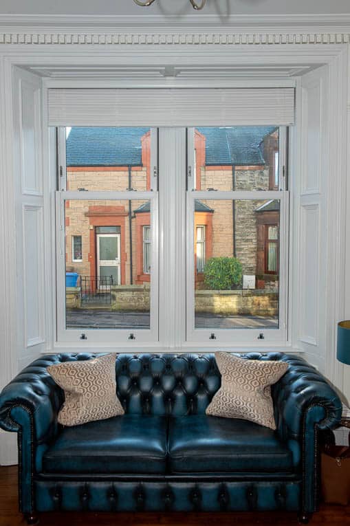 Living room with blue chesterfield sofa and white sliding sash windows