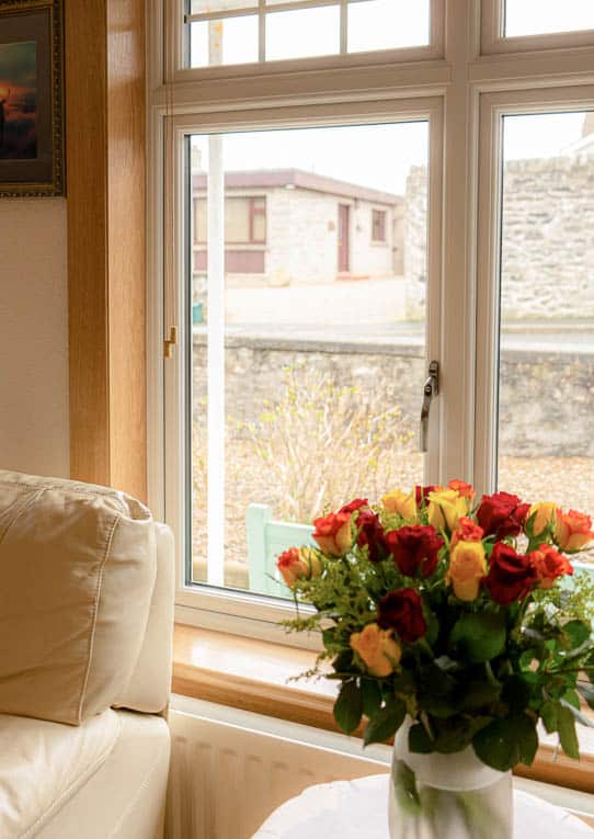 Close up of white casement window and a vase of red and yellow roses