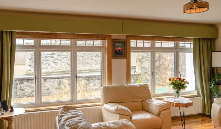 Living room with two white casement windows with royal oak sills and surrounds and green curtains