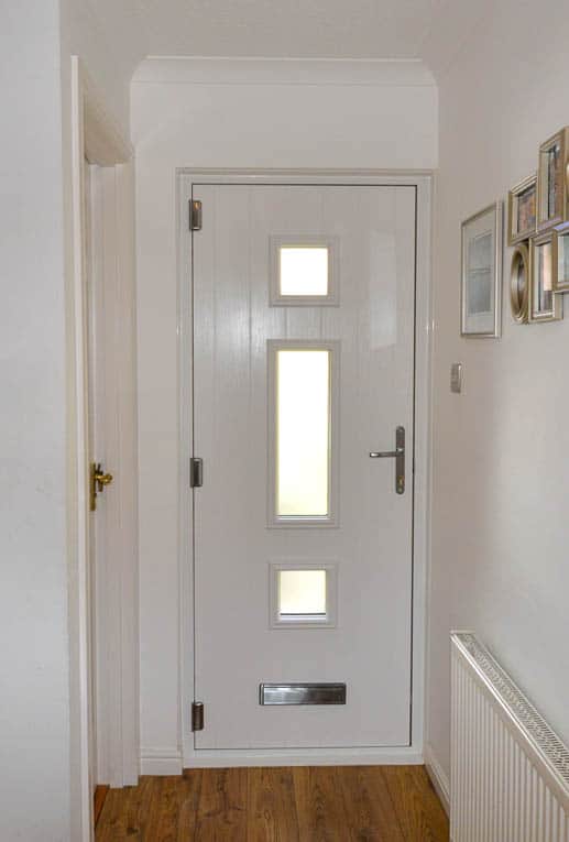 Internal view of front door. White engineered timber door with three windows panels.