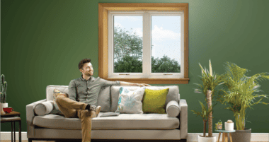 Man sitting on the sofa in front of a white casement window