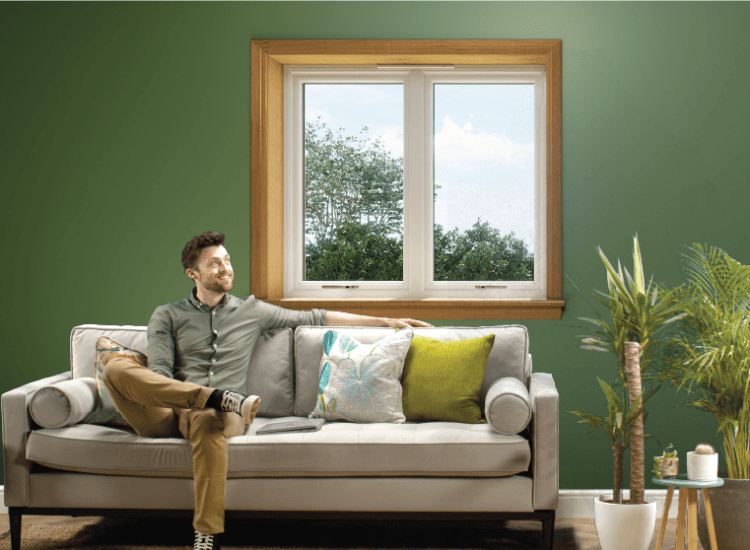 Man sitting on the sofa in front of a white casement window