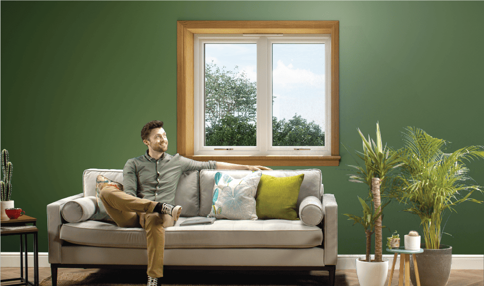 Man sitting on the sofa in front of a white casement window