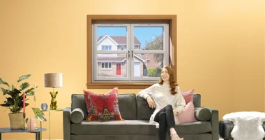 Woman sitting on sofa in living room with white casement windows