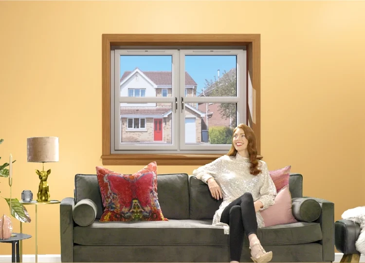 Woman sitting on sofa in living room with white casement windows