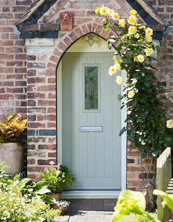 A duck egg blue TimberLuxe engineered timber door with a central, decorative glass pane, complete with a stainless steel letterbox. The door is positioned within a brick alcove.