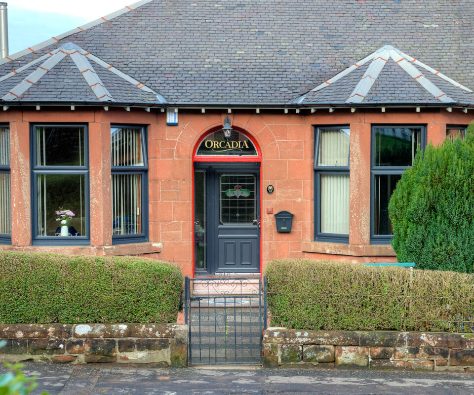 External image of a red sandstone bungalow with new anthracite grey casement windows located.