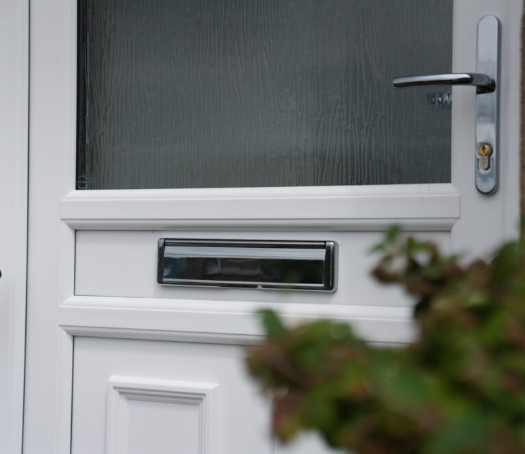 close up exterior shot of white Lorimer uPVC front door complete with frosted glass and silver hardware