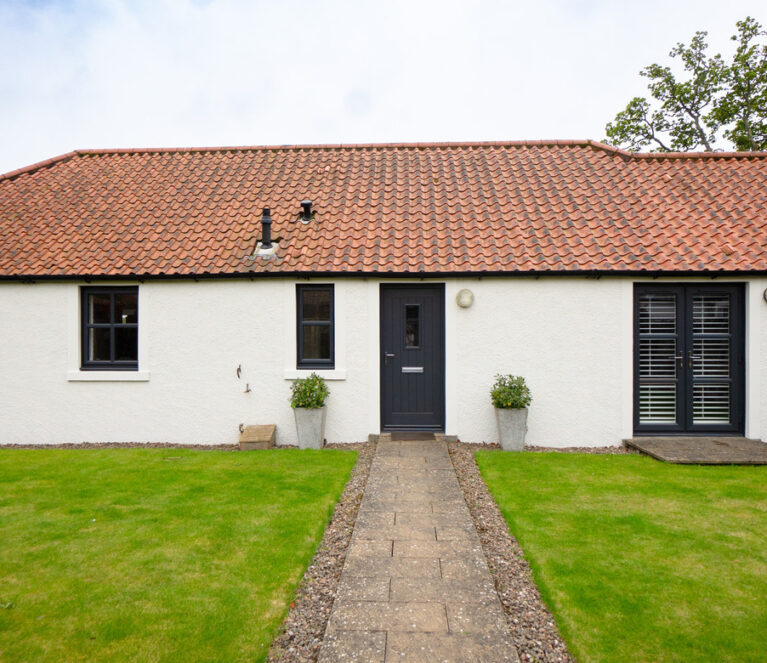Exterior of traditional cottage with anthracite grey Lorimer casement windows, Timberluxe front door and French doors.