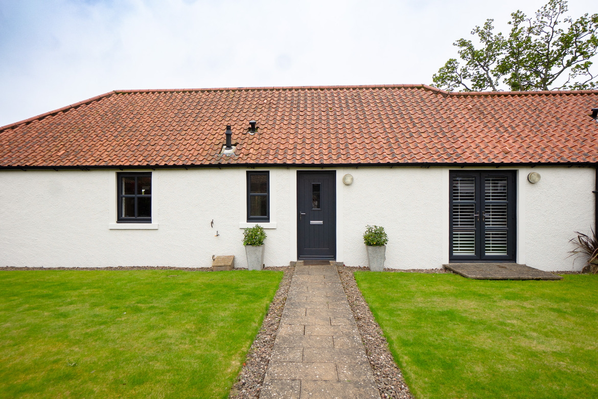 Exterior of traditional cottage with anthracite grey Lorimer casement windows, Timberluxe front door and French doors.