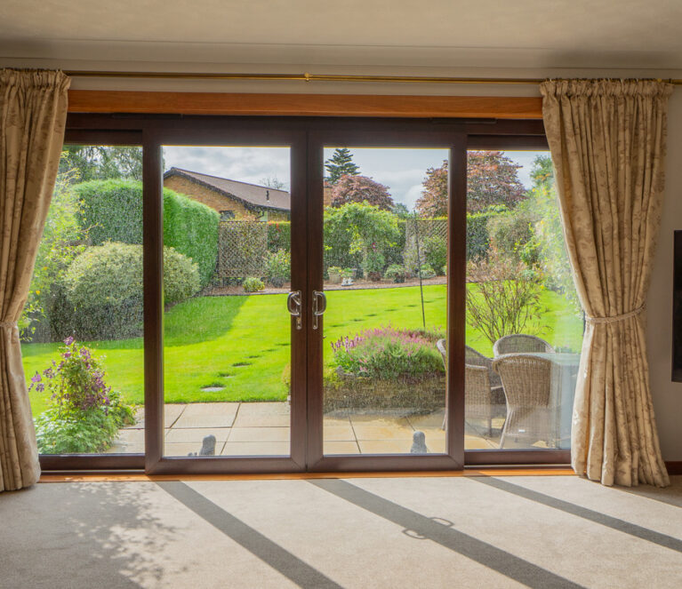 Interior view of rosewood Lorimer patio doors overlooking the garden in Doune