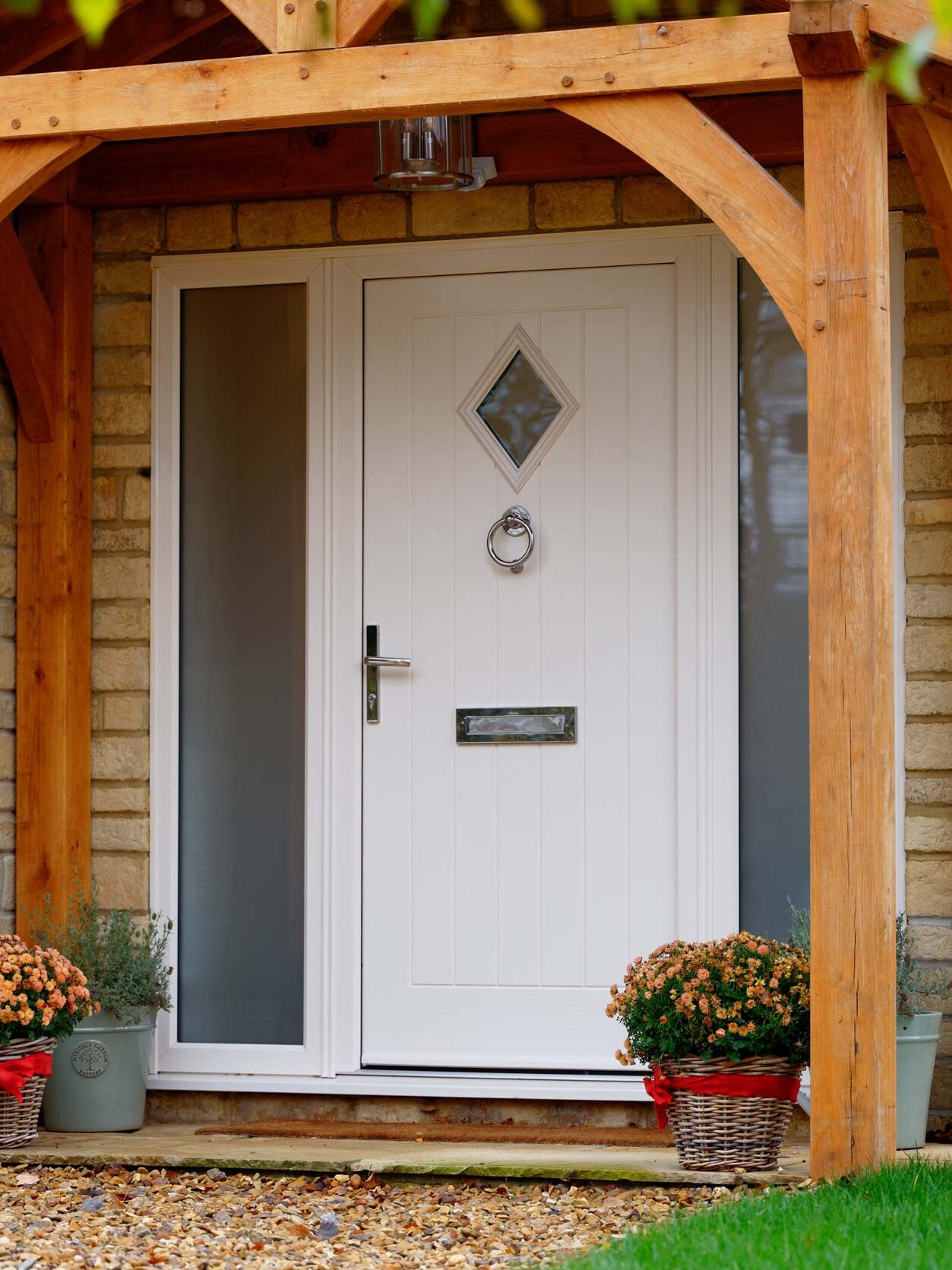 Exterior shot of a white TimberLuxe front door, complete with two frosted glass side screens.