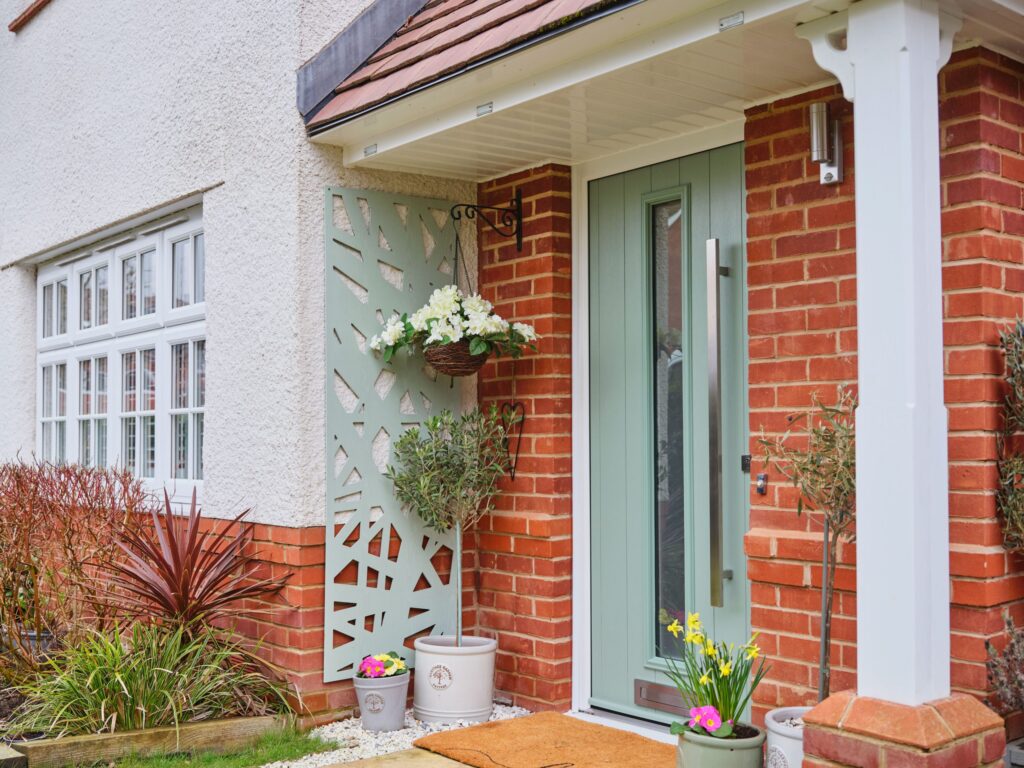 Exterior shot of a TimberLuxe front door in Chartwell Green, complete with a graphite pull bar handle.