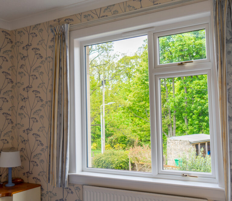Internal view of lorimer casement windows in Falkland home bedroom, complete with gold handles and painted white sill and surrounds.
